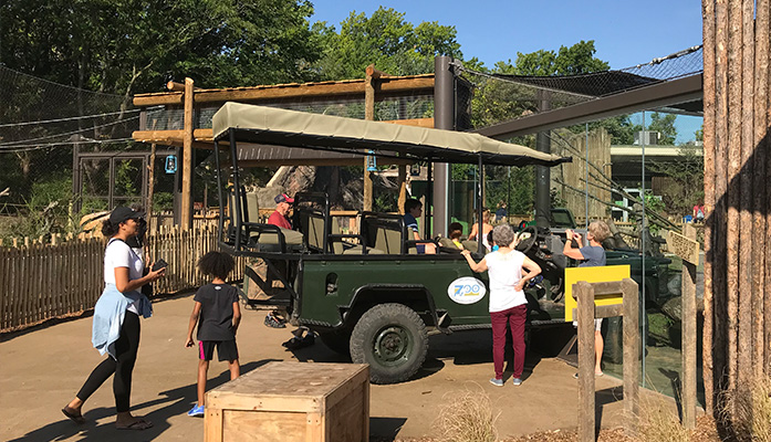 People at zoo exhibit with vehicle
